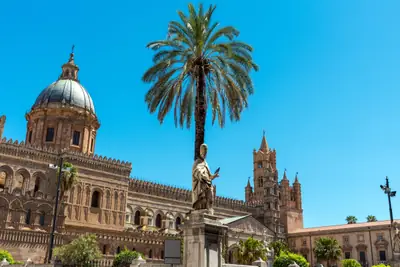 Zabytkowa budowla z kopułą i palma w Palermo